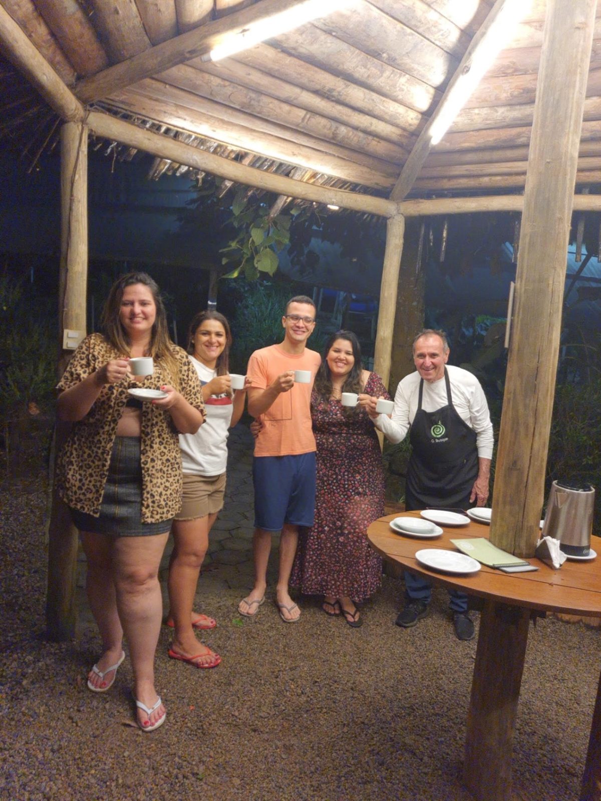 Visitantes brindando com xícaras de chá no quiosque à noite